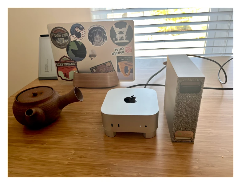 Figure 1: The DGX next to my Mac Mini, with a tea pot (and a 13-inch MacBook Air) for scale. Both have roughly the same size and are super quiet (which is great for office or desk use).